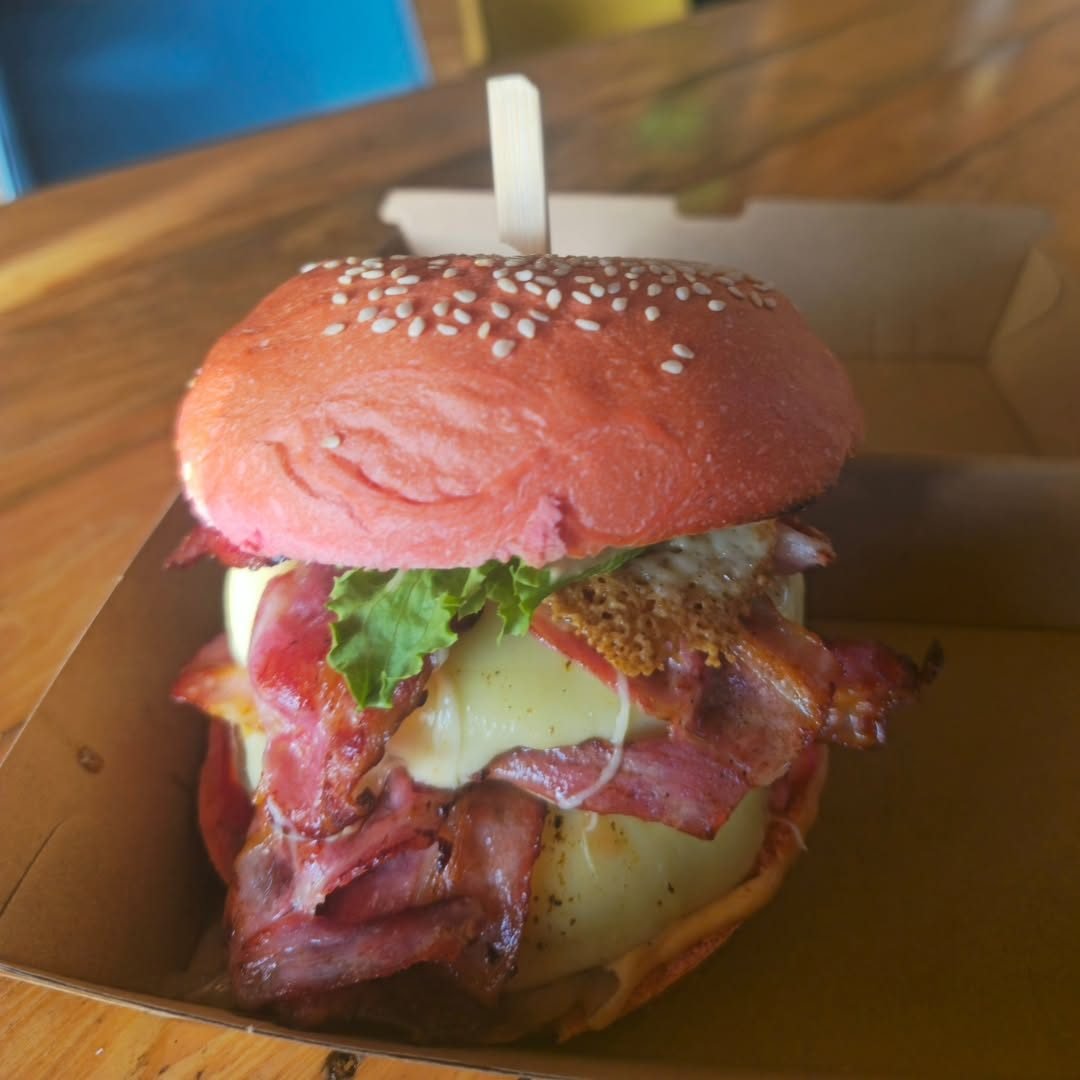 Burger au pain rose, bacon et fromage fondu dans sa boîte